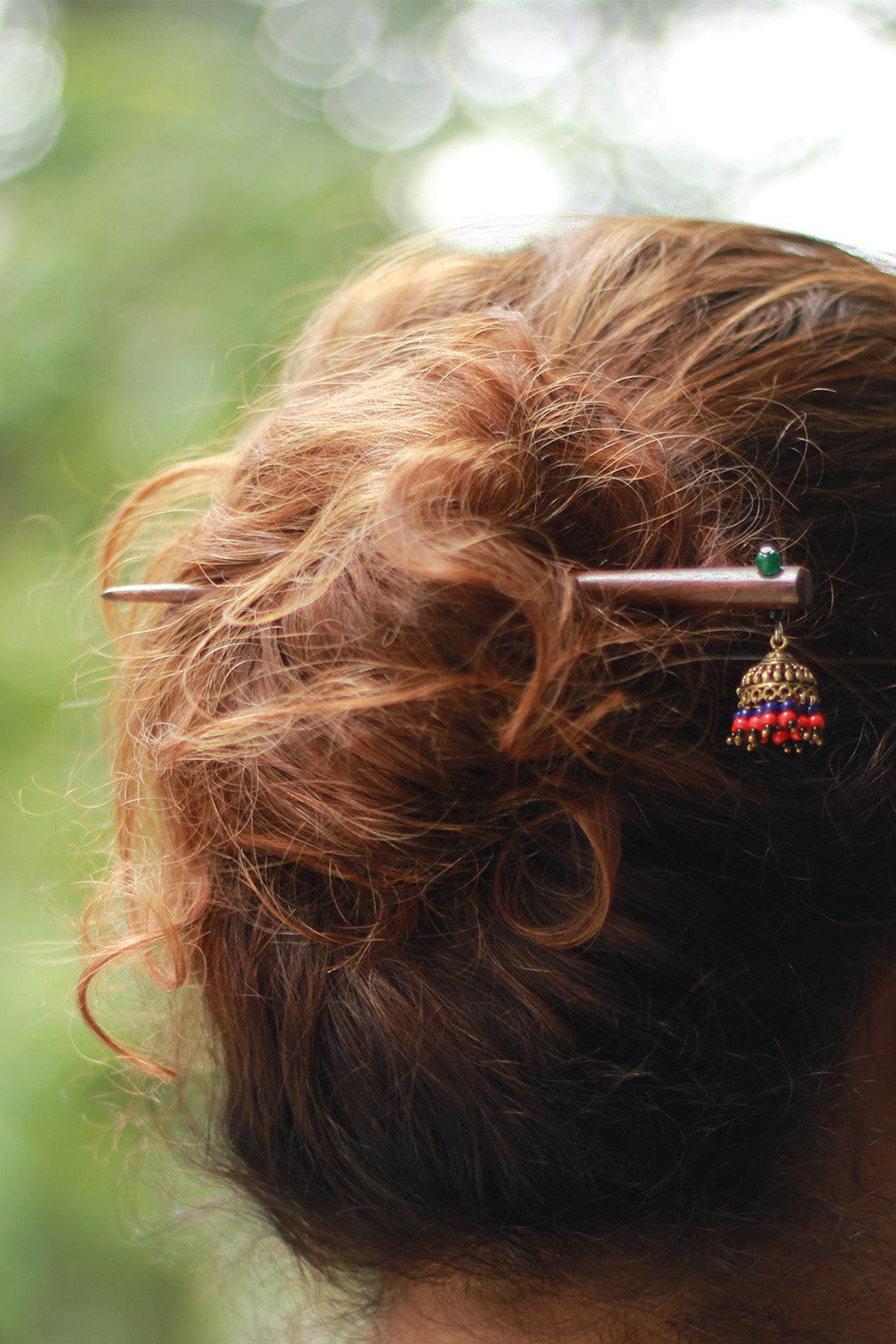 Close-up of a hairpin with decorative elements in a person's hair against a blurred natural background
