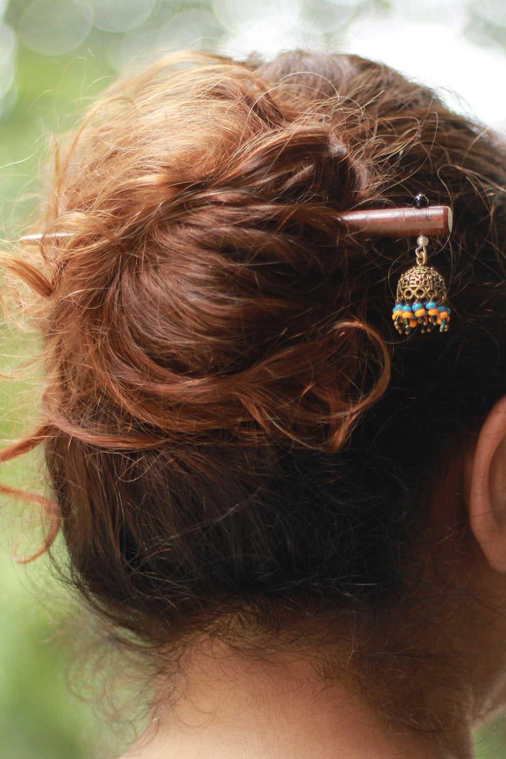 Close-up of a decorative hair pin in a person's hair with a blurred natural background