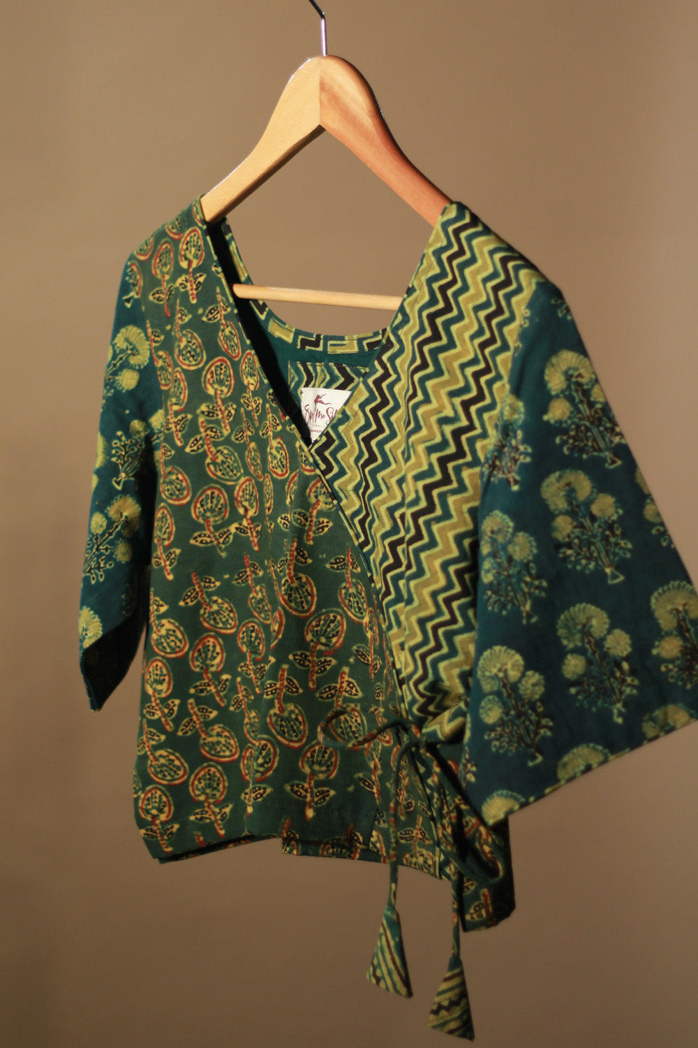 Green patterned garment on a hanger against a brown background