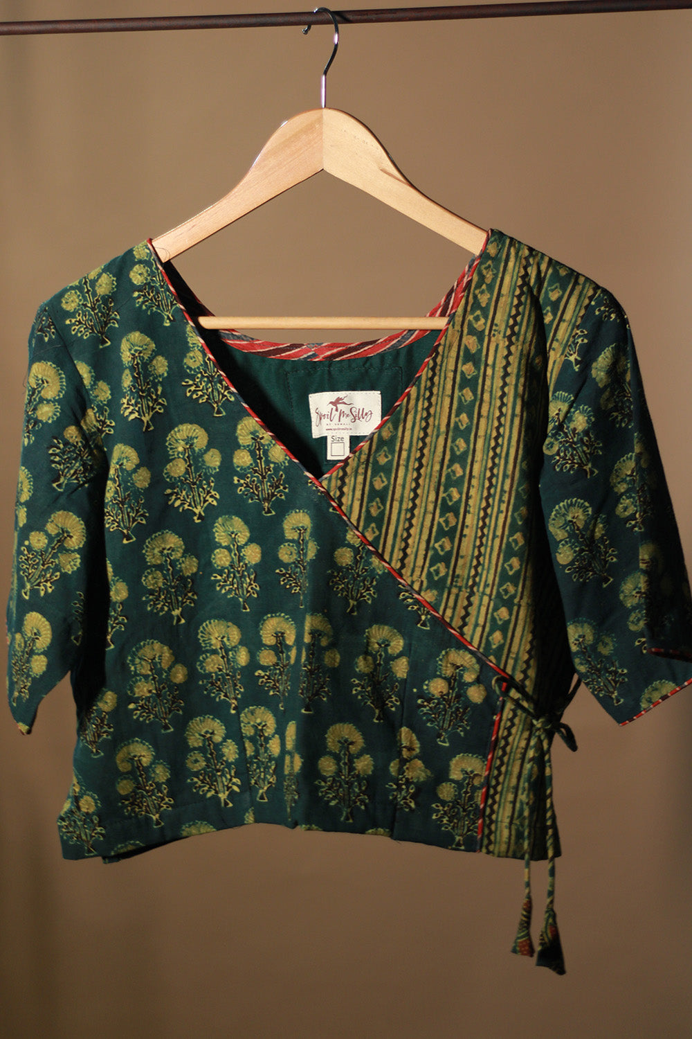 Green patterned top on a wooden hanger against a beige background