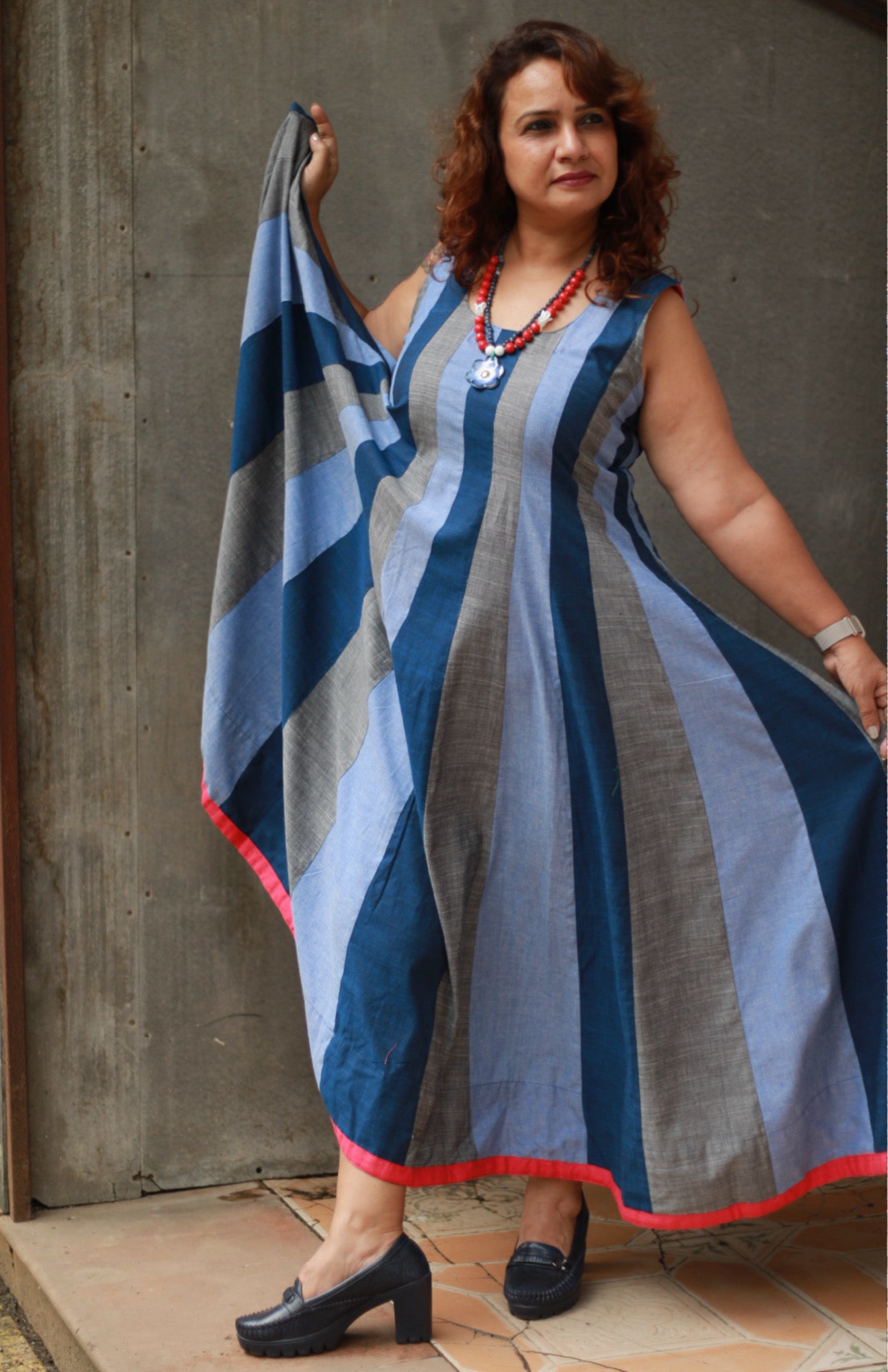 Woman wearing a long, striped dress with a neutral background