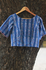 Blue patterned blouse on a hanger against a tree trunk