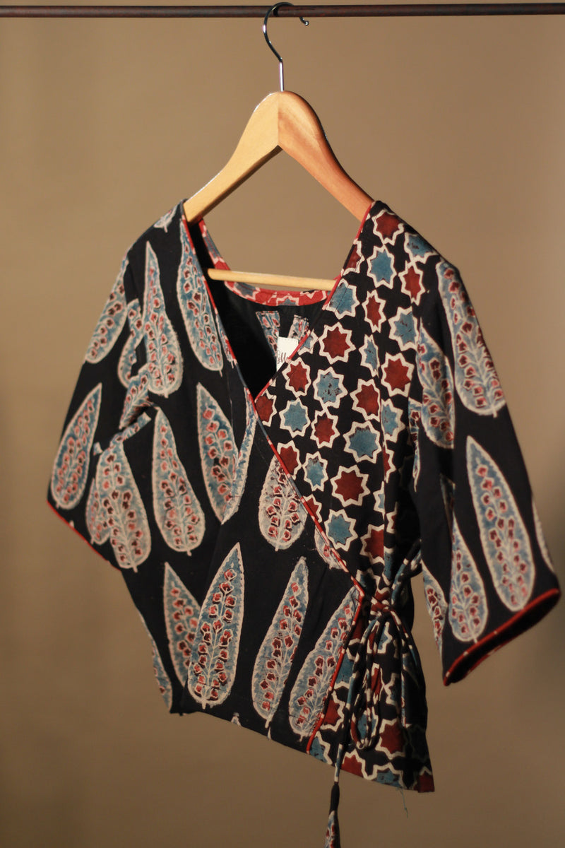 Patterned top on a hanger against a plain background