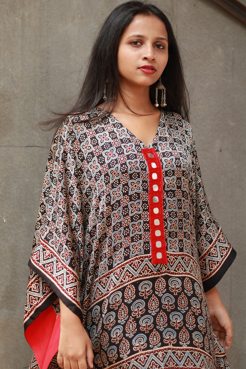 Woman wearing a patterned dress with a red accent against a gray background