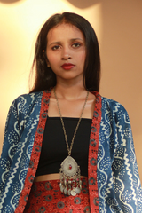 Woman wearing a blue patterned jacket with a red and black outfit underneath, against a plain background.